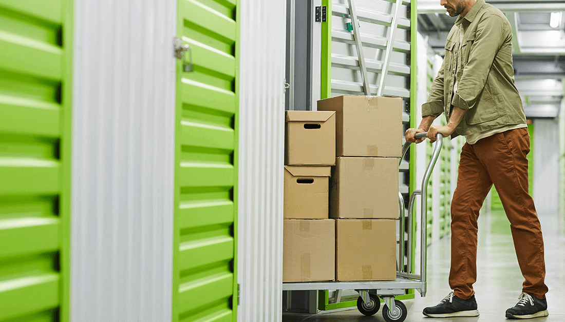 man pushing storage boxes into a long term self storage unit