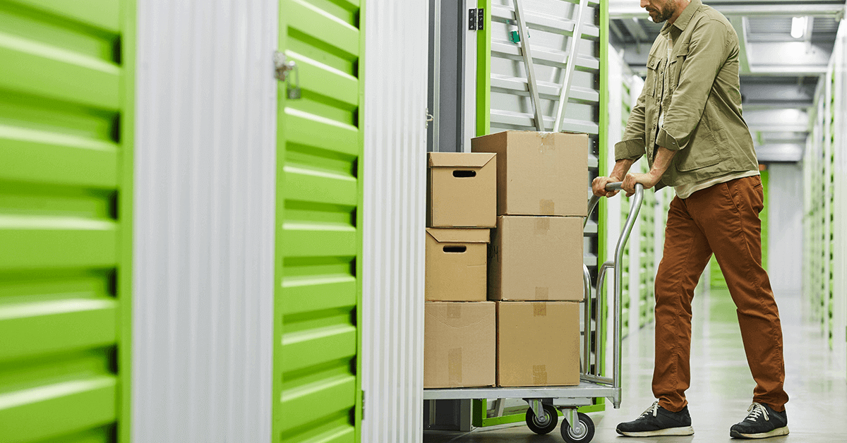 man pushing storage boxes into a long term self storage unit